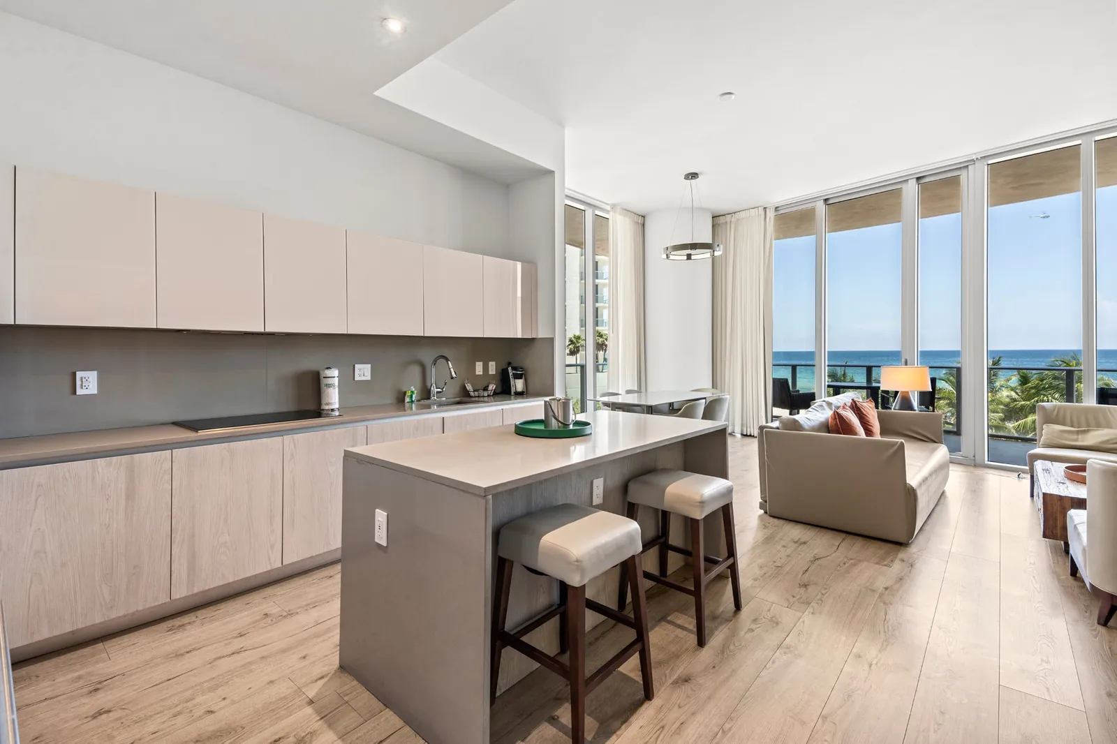 Cocina abierta y sala con ventanales de piso a techo frente al océano en Hallandale Beach